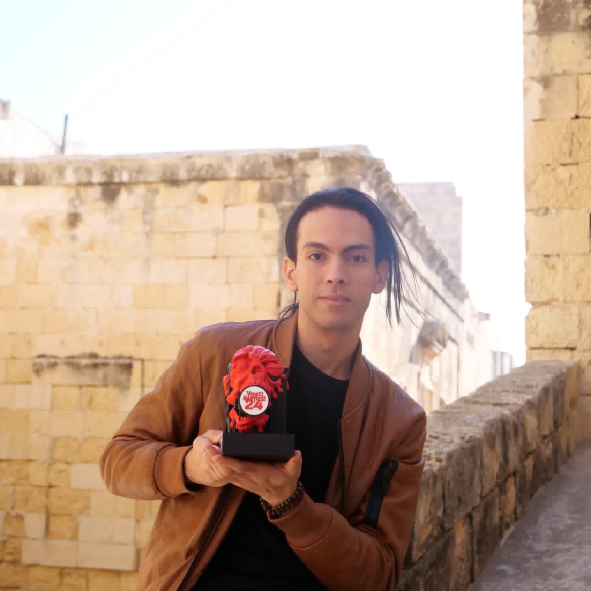 Dhia Akermi holding the Video Nasties 2024 Best Movie Idea trophy in Malta